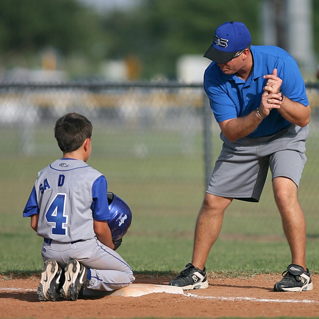 man kneeling on baseball field beside man