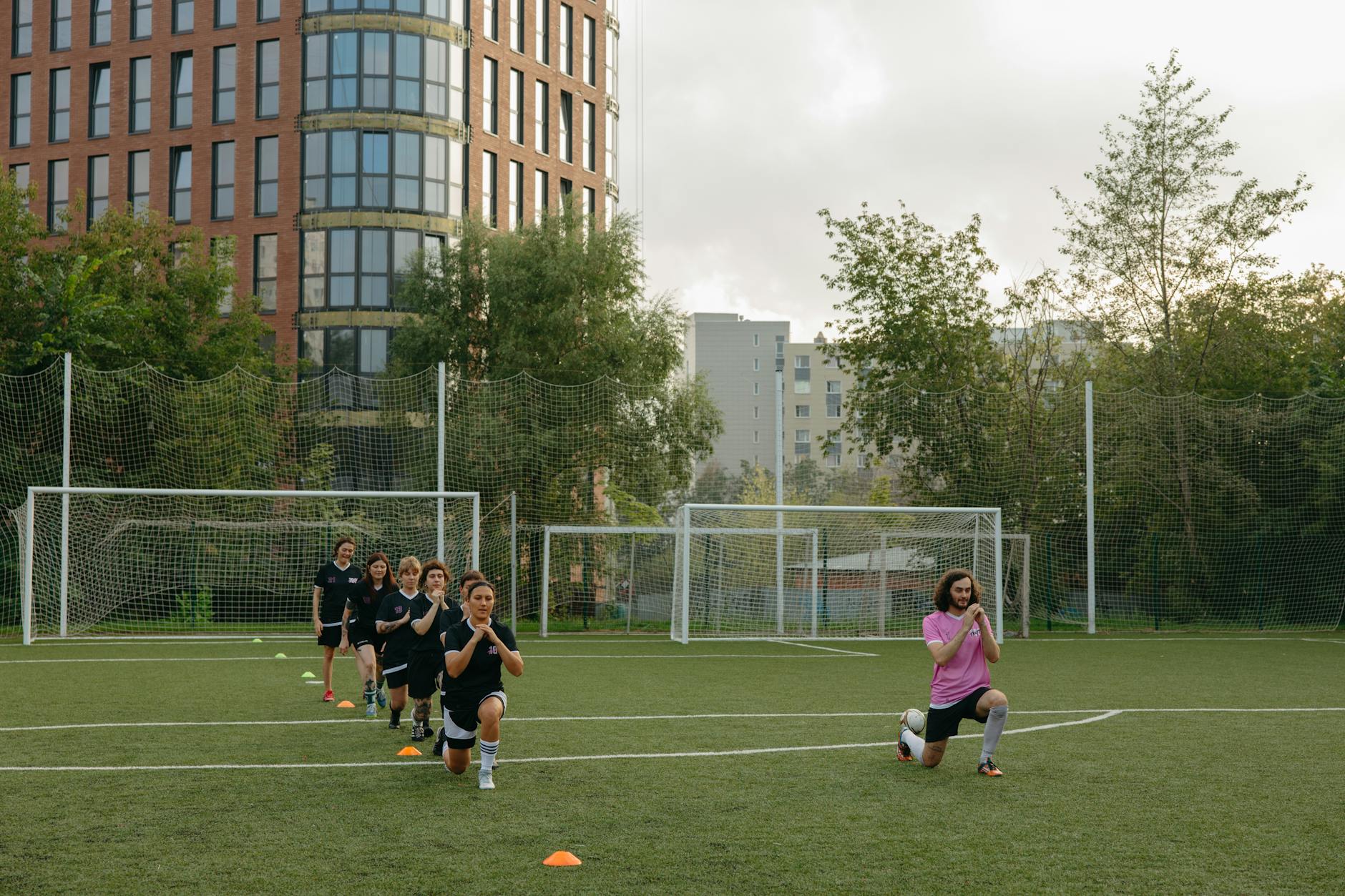 A group of young people being taken through football training drills.